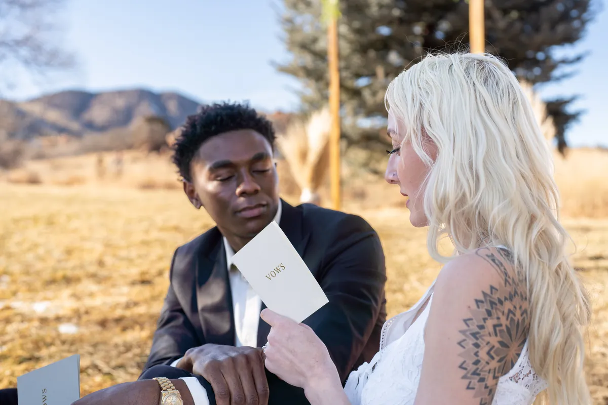 A couple reading their vows together in golden Colorado light.